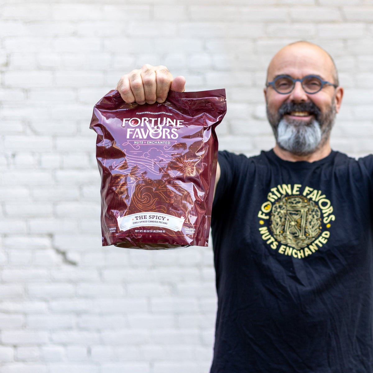 Person smiling and holding 5lb bulk bag of The Spicy candied pecans