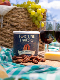 Fortune Favors The Mesquite Can at picnic with basket, charcuterie board on blue blanket with wine in glasses