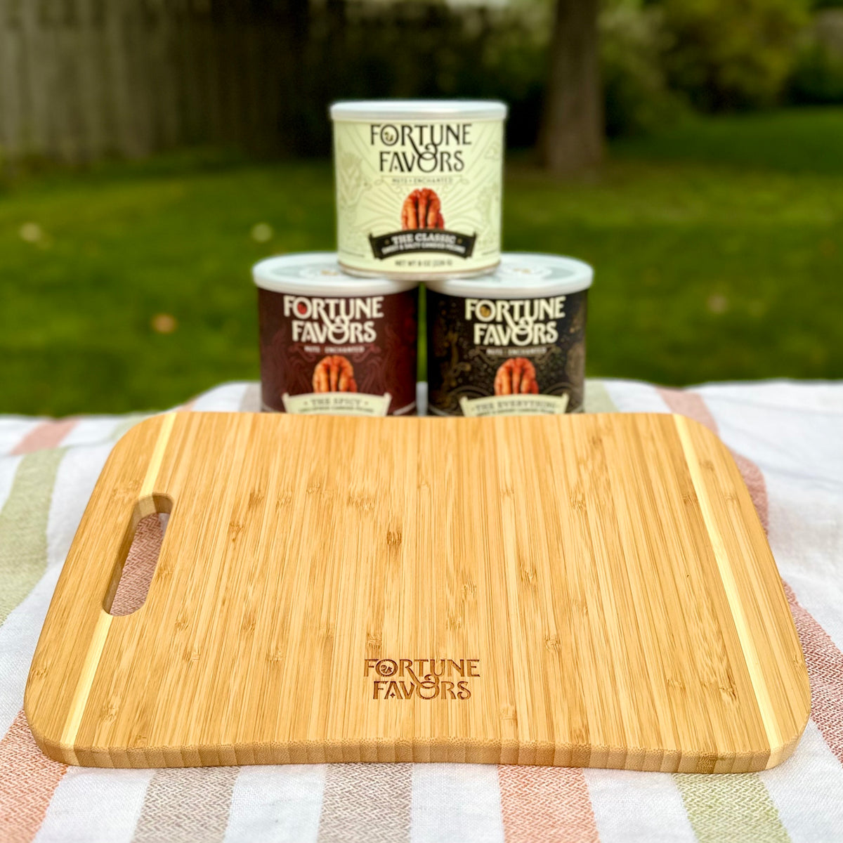 FF Charcuterie Board in front of cans of The Classic, The Spicy and The Everything in an outdoor setting