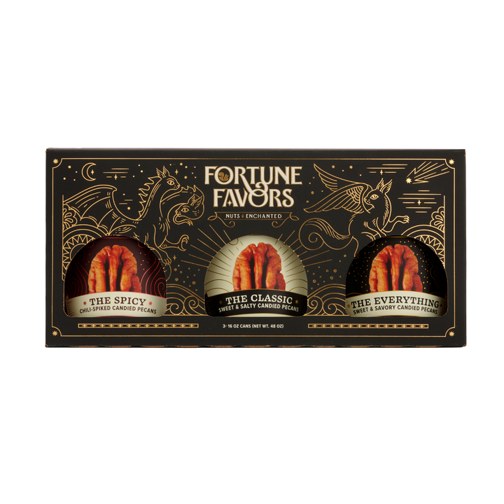 Black and gold sampler gift pack containing three 16 ounce cans of Fortune Favors candied pecans, one of each signature flavor.